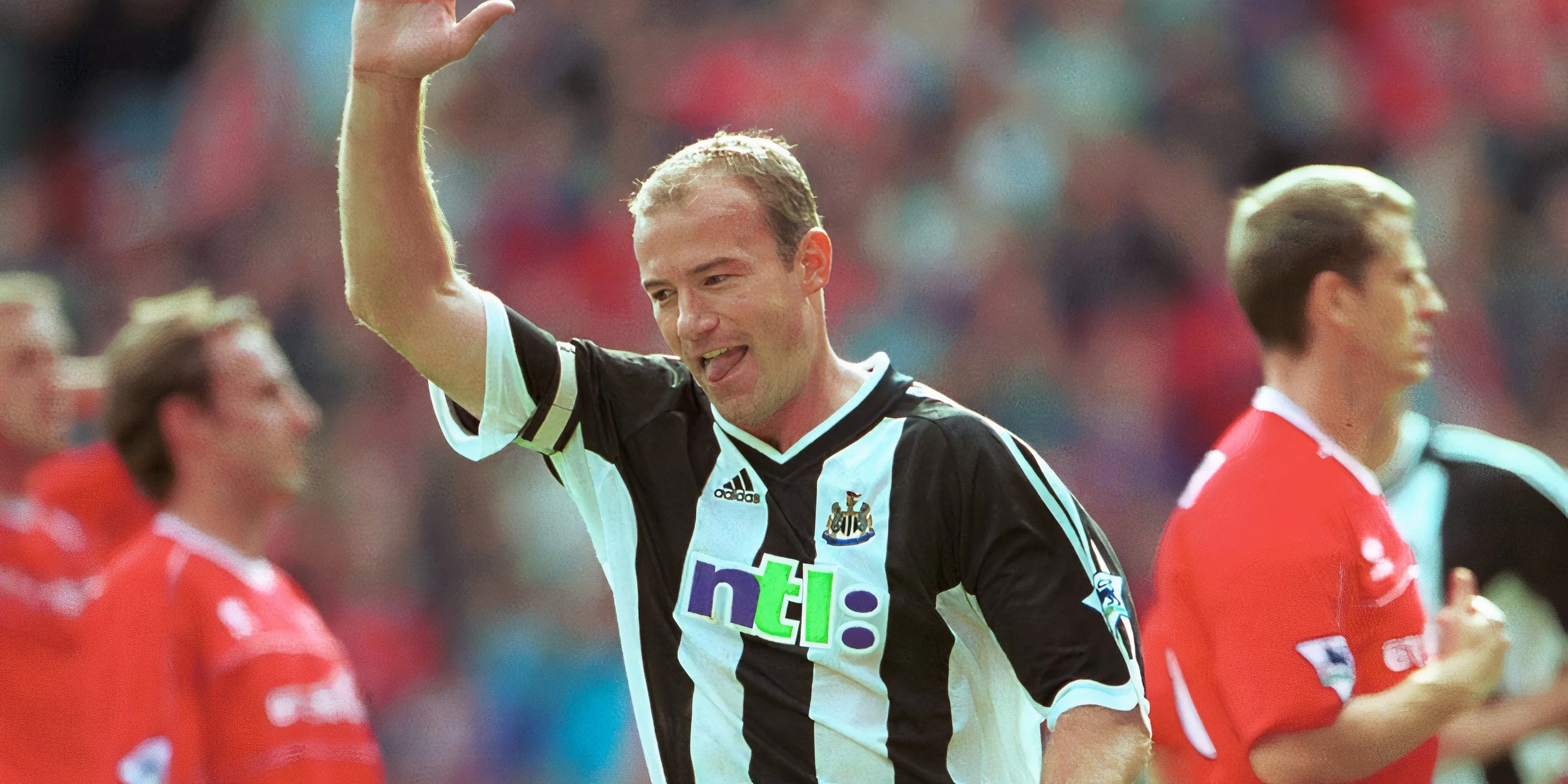 Tiền đạo Alan Shearer trong màu áo Newcastle United ăn mừng bàn thắng bằng cách giơ một tay lên cao, biểu tượng của người ghi bàn hàng đầu Premier League.